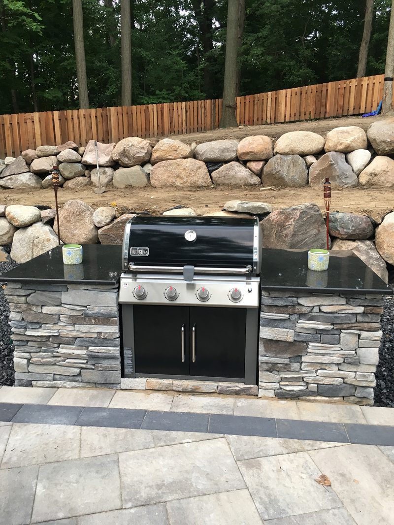 Outdoor kitchen with stone veneer and boulder wall